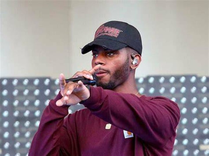 Close up of Bryson Tiller in a black shirt and earrings